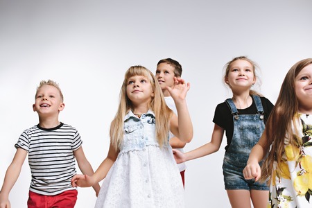 Group of fashion cute preschooler kids friends posing together and looking at camera on a white studio background. The friendship, fashion, summer concept. Space for text.の写真素材