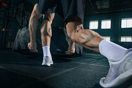 Shirtless young fit man flipping heavy tire at gym. The exercise, fitness, sport, workout, athlete, power, training, bodybuilding conceptの写真素材