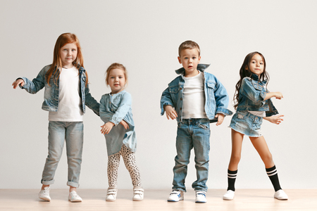 The portrait of cute little kids boy and girls in stylish jeans clothes looking at camera against white studio wall. Kids fashion and happy emotions conceptの写真素材