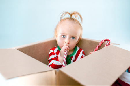 Cute baby girl 1 year old sitting in box over Christmas background. Holiday, celebration, kid conceptの写真素材