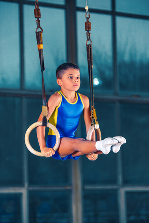Full length shot of male athlete performing pull-ups on gymnastic rings.の写真素材