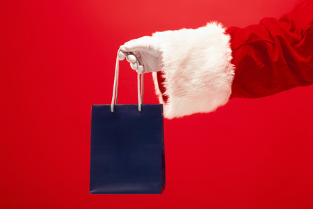 The hand of santa claus holding a gift on redの写真素材