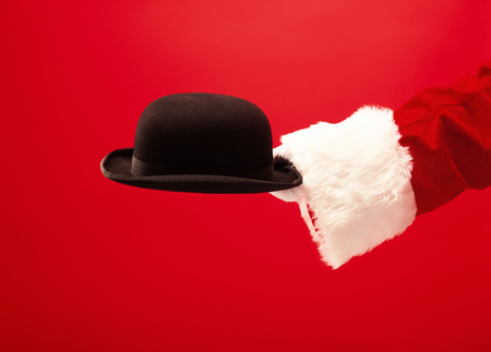 The hand of santa claus holding a black hat on redの写真素材