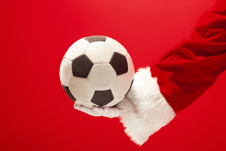 Santa Claus holding a football ball isolated on red studioの写真素材