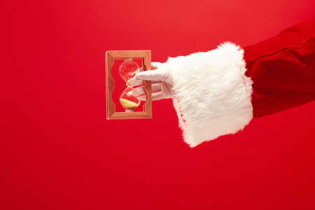 Santa holding an old sand clock on redの写真素材