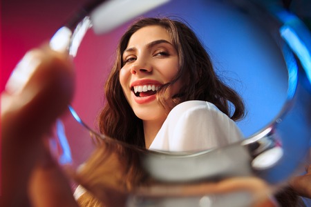 The happy young woman. Emotional female cute face. View from the glass