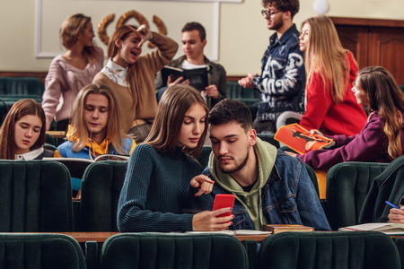 The group of cheerful students sitting in a lecture hall before lesson. The education, university, lecture, people, institute, college, studying, friendship and communication conceptの写真素材