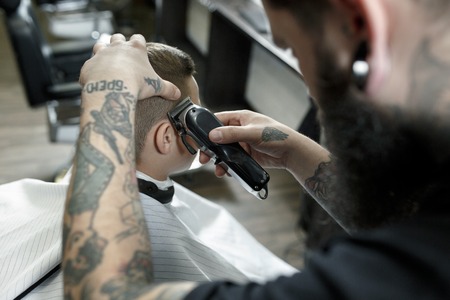 Children hairdresser cutting little boys hair. Contented cute preschooler boy getting the haircut.