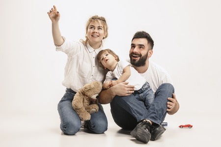 The happy family with kid sitting together and smiling at camera isolated on white studio backgroundの写真素材