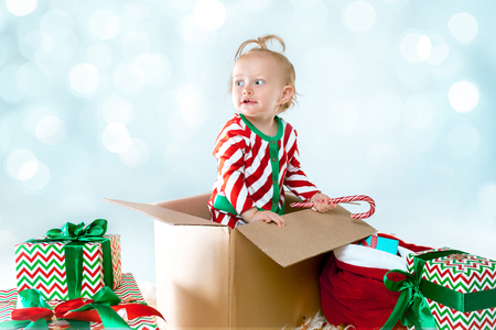 Cute baby girl 1 year old sitting in box over Christmas background. Holiday, celebration, kid conceptの写真素材