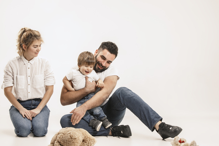The happy family with kid sitting together and smiling at camera isolated on white studio backgroundの写真素材