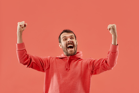 I won. Winning success happy man celebrating being a winner. Dynamic image of caucasian male model on coral studio background. Victory, delight concept. Human facial emotions concept. Trendy colorsの写真素材