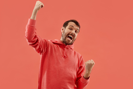 I won. Winning success happy man celebrating being a winner. Dynamic image of caucasian male model on coral studio background. Victory, delight concept. Human facial emotions concept. Trendy colorsの写真素材