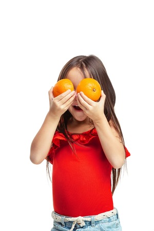 Full length portrait of cute little kid girl in stylish jeans clothes with orange standing against white studio wall. Kids fashion conceptの写真素材