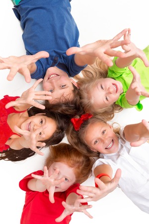 Close-up of happy children lying on floor in studio and looking up, isolated on white background, top view. Kids emotions and fashion conceptの写真素材