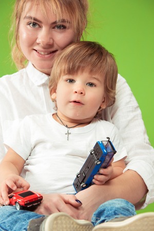 The happy family with kid drawing with pencils and posing together on green studio backgroundの写真素材