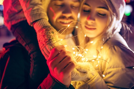 Adult couple hanging out in the city during Christmas time over lights city background and snow at nightの写真素材