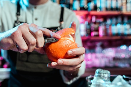 Expert barman is making cocktail at night club or bar. Glass of fiery cocktail on the bar counter against the background of bartenders hands with fire. Barman day conceptの写真素材