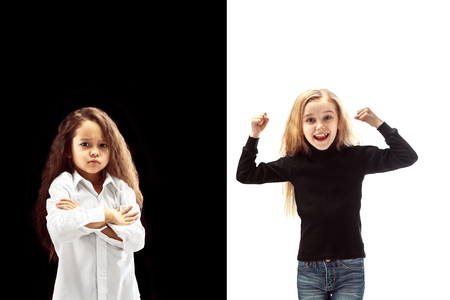 The portrait of emotional happy winner girl and serious girl on a white and black studio