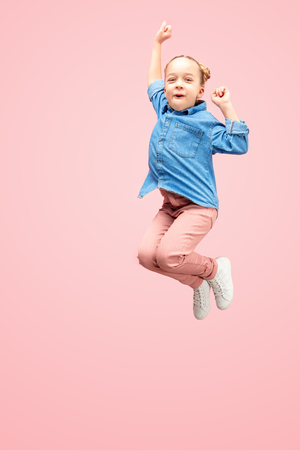 Young happy caucasian teen girl jumping in the air, isolated on pink studioの写真素材