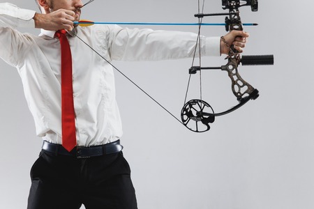 Businessman aiming at target with bow and arrow, isolated on gray studioの写真素材