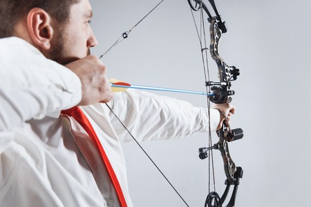 Businessman aiming at target with bow and arrow, isolated on gray studioの写真素材