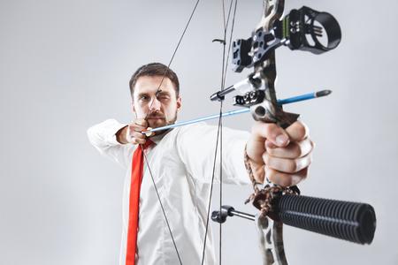 Businessman aiming at target with bow and arrow, isolated on gray studioの写真素材