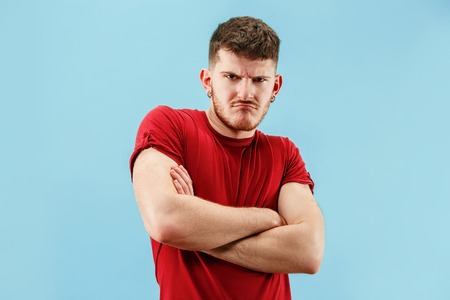 The sad emotional angry man screaming on blue studio background. Emotional, young face. male half-length portrait. Human emotions, facial expression concept. Trendy colorsの写真素材