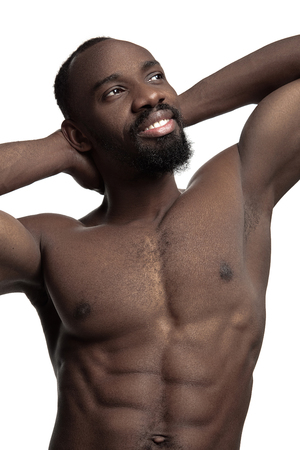 Portrait of a young naked happy smiling african man at studio. High Fashion male model posing and isolated on white backgroundの写真素材