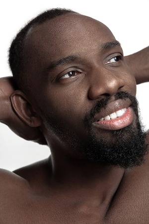 Portrait of a young naked happy smiling african man at studio. High Fashion male model posing and...
