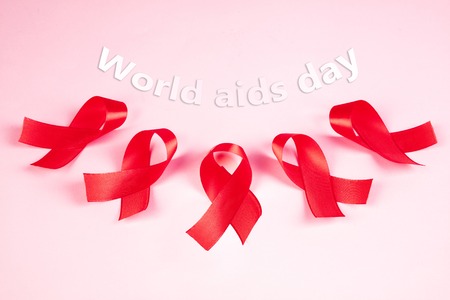 Aids Awareness Sign Red Ribbons on pink background . World Aids Day concept. The health, help, care,...