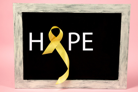 Yellow ribbon symbolic color for Sarcoma Bone cancer awareness and suicide prevention on aged wooden advertising board. The cancer, health, help, care, support, hope, illness, healthcare conceptの写真素材