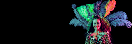 Beautiful young woman in carnival peacock costume. Beauty model woman at party over holiday background with magic glow. Christmas and New Year celebration. Glamour lady with perfect make up and hairstyleの写真素材