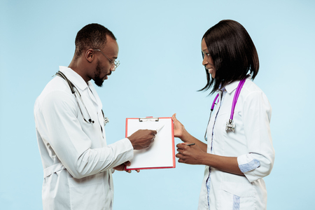 The female and male smiling happy afro american doctors on blue background at studio.The clinic, medical, nurse, health, healthcare, hospital, care, job, professional conceptの写真素材