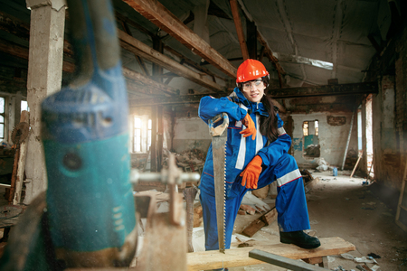 Destroying gender stereotypes. Woman wearing helmet using different male work tools. Gender equality. Girl working at flat remodeling. Building, repair and renovation. woman in the male professionの写真素材