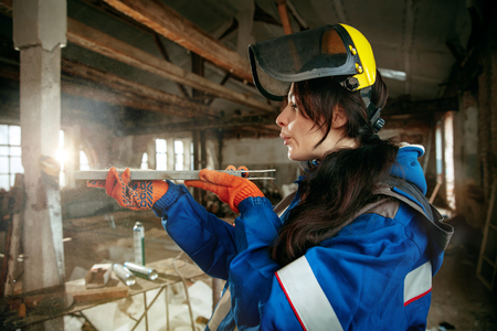 Destroying gender stereotypes. Woman wearing helmet using different male work tools. Gender equality. Girl working at flat remodeling. Building, repair and renovation. woman in the male professionの写真素材