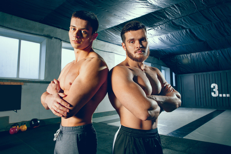 My friend. The young two men resting and looking at camera after training session in gym. Healthy lifestyle and friendship conceptの写真素材