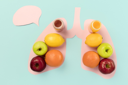 Detox food selection from fresh fruits in paper human lungs on blue background. Healthy food nutrition. Conceptual composition with copyspaceの写真素材