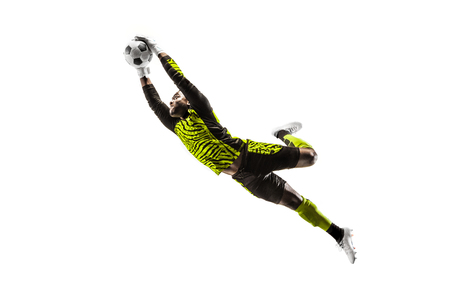 Male soccer player goalkeeper catching ball in jump. Silhouette of fit man with ball isolated on white studio backgroundの写真素材