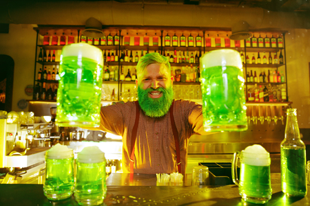 Saint Patricks Day Party. Happy friends is celebrating and drinking green beer. Young men and women...
