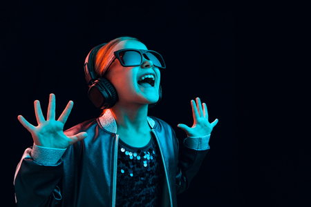 Neon portrait of young girl with headphones enjoying music. Lifestyle of young people, human emotions, childhood, happiness concept.の写真素材