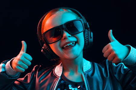 Neon portrait of young girl with headphones enjoying music. Lifestyle of young people, human emotions, childhood, happiness concept.の写真素材