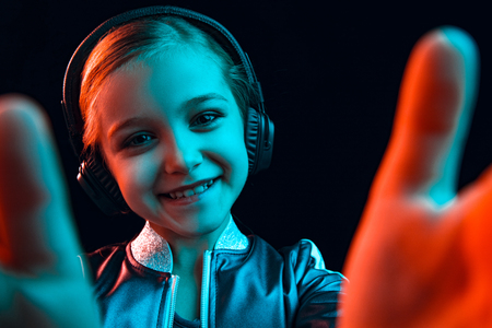 Neon portrait of young girl with headphones enjoying music. Lifestyle of young people, human emotions, childhood, happiness concept.の写真素材