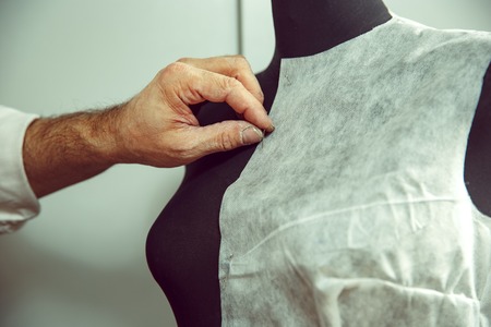 Closeup of tailors table with male hands tracing fabric making pattern for clothes in traditional atelier studio. The man in female profession. Gender equality conceptの写真素材