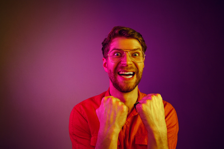 I won. Winning success happy man celebrating being a winner. Dynamic image of caucasian male model on blue studio background. Victory, delight concept. Human facial emotions concept. Neon trendy colorsの写真素材