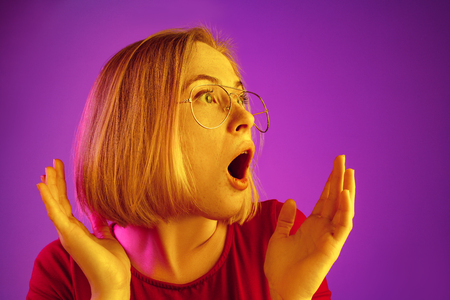 Wow. Beautiful female half-length front portrait isolated on neon studio backgroud. Young emotional surprised woman standing with open mouth. Human emotions, facial expression concept. Trendy colorsの写真素材