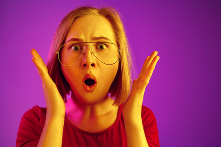Wow. Beautiful female half-length front portrait isolated on neon studio backgroud. Young emotional surprised woman standing with open mouth. Human emotions, facial expression concept. Trendy colorsの写真素材