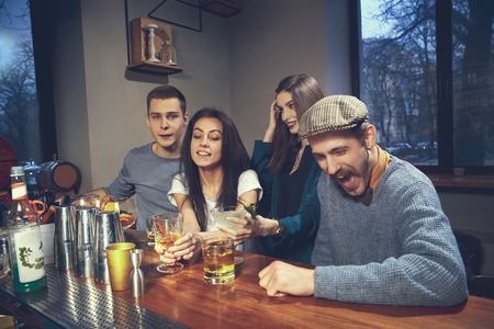 Photo of joyful friends in the bar or at pub communicating with each otherの写真素材