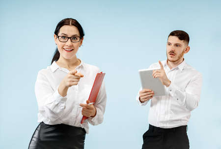Concept of partnership in business. Young happy smiling man and woman standing against blue background at studioの写真素材