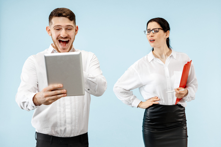 Concept of partnership in business. Young emotional man and woman against blue background at studio. Human emotions and partnership conceptの写真素材